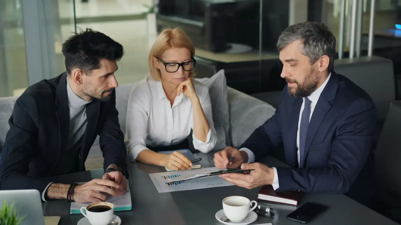 Three professionals reviewing charts and documents together at a table